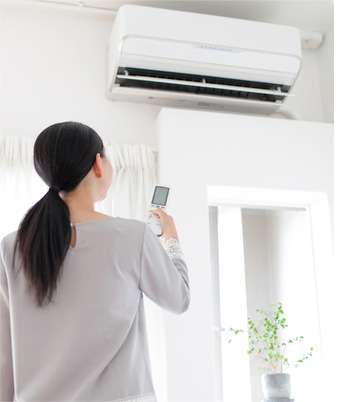 asian lady controlling air conditioner keeping cool air inside insulated walls